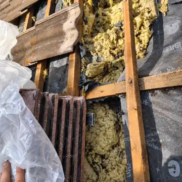Zdjęte dachówki, pod nimi podarta membrana i zniszczona wełna