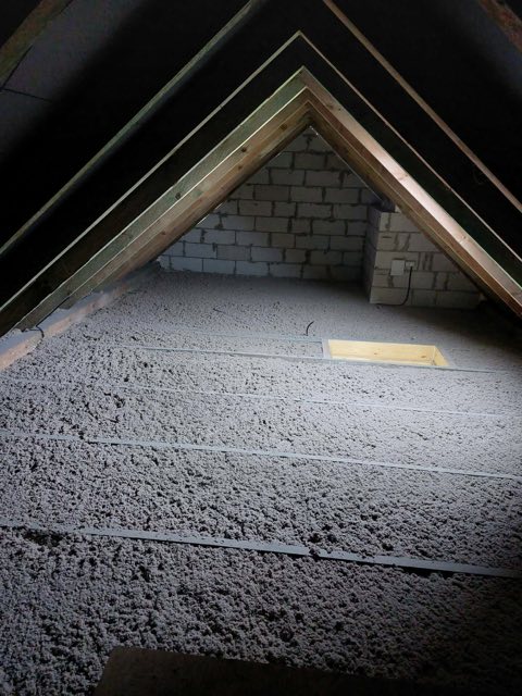 Poddasze po docieplaniu celulozą, równa szara warstwa izolacji od ściany szczytowej po okap